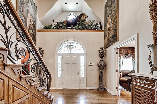 foyer featuring high vaulted ceiling and dark wood-type flooring