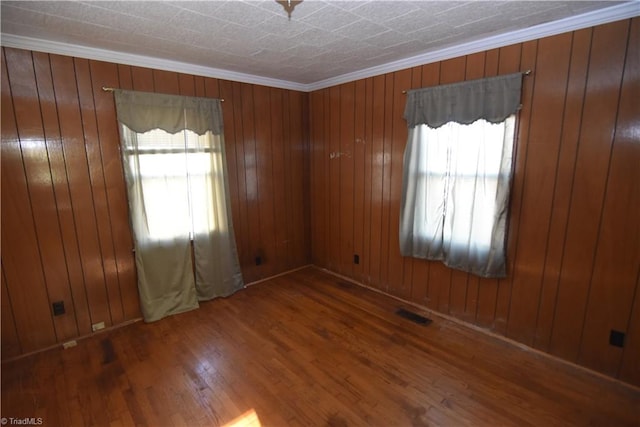 spare room featuring ornamental molding, wood walls, and dark wood-type flooring