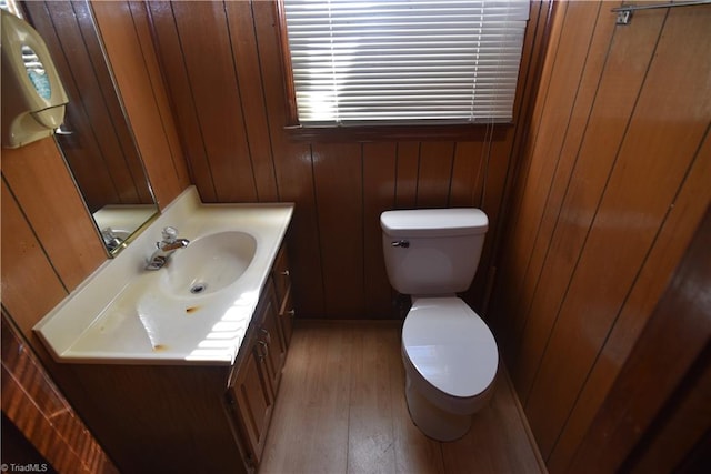 bathroom with wooden walls, hardwood / wood-style flooring, vanity, and toilet