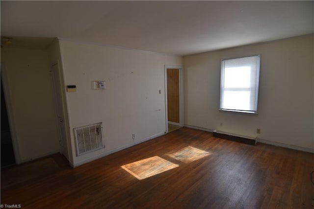 spare room with baseboard heating and dark hardwood / wood-style flooring