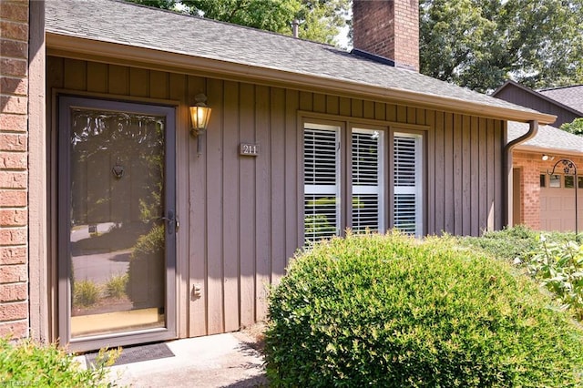 211 Chadbourne Dr, Winston-Salem, NC 27104 - doorway to property with a chimney, a shingled roof, an attached garage, and board and batten siding