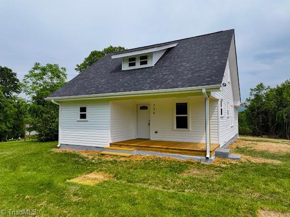 view of front of home featuring covered porch, a front yard, and a shingled roof