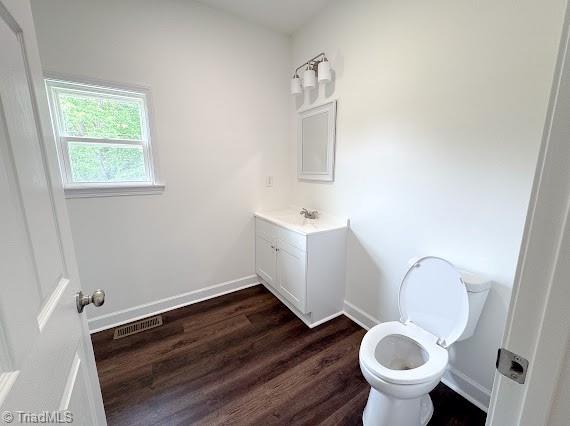 bathroom with wood finished floors, vanity, toilet, and baseboards