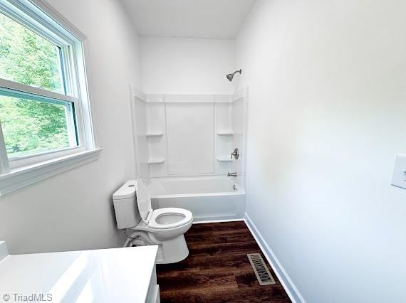 bathroom with toilet, vanity, wood finished floors, and shower / bathtub combination