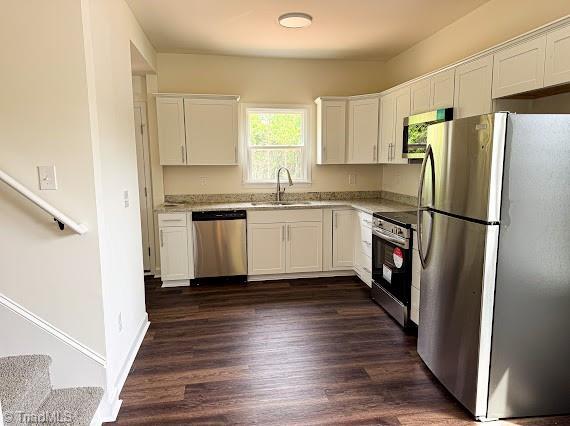 kitchen with stainless steel appliances, a sink, white cabinetry, and dark wood finished floors