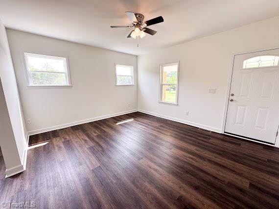 entryway featuring plenty of natural light, ceiling fan, baseboards, and dark wood-type flooring