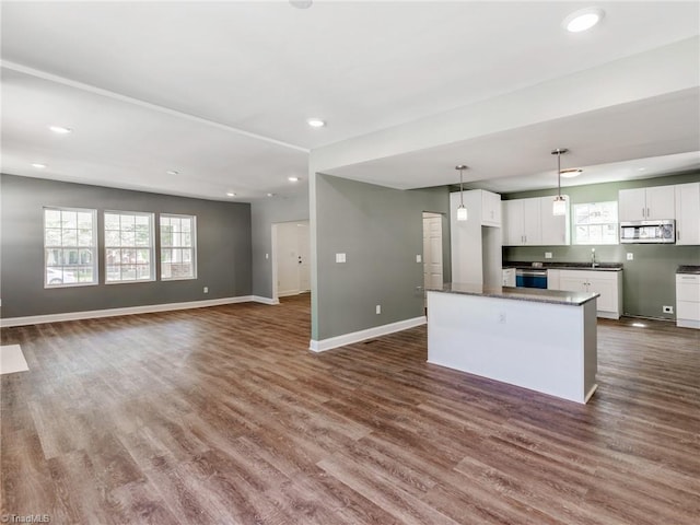 kitchen with a kitchen island, dark hardwood / wood-style flooring, white cabinetry, sink, and pendant lighting