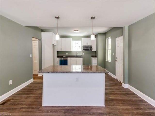 kitchen featuring dark hardwood / wood-style flooring, appliances with stainless steel finishes, white cabinetry, and pendant lighting