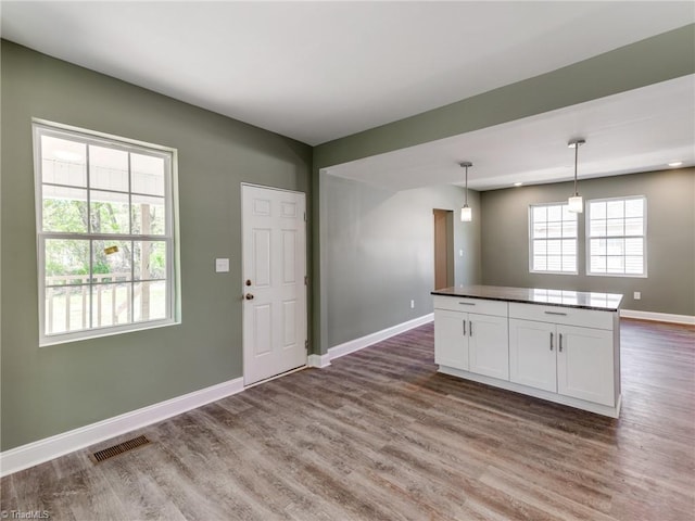 kitchen featuring white cabinets, a kitchen island, hardwood / wood-style flooring, and hanging light fixtures