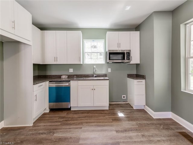 kitchen featuring white cabinets, sink, stainless steel appliances, and dark wood-type flooring