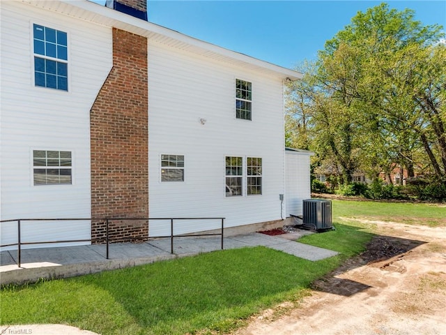 back of property with central AC unit and a lawn