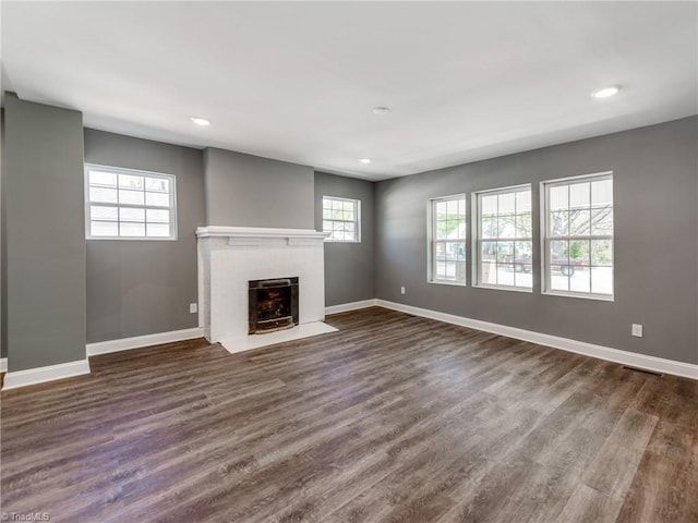 unfurnished living room featuring a healthy amount of sunlight and dark wood-type flooring