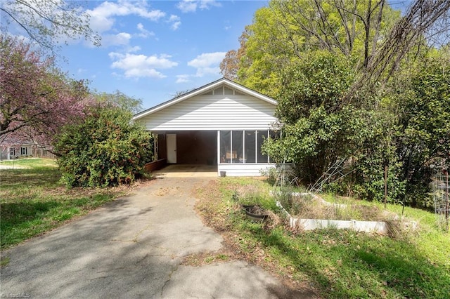exterior space featuring driveway, a sunroom, a vegetable garden, and a carport