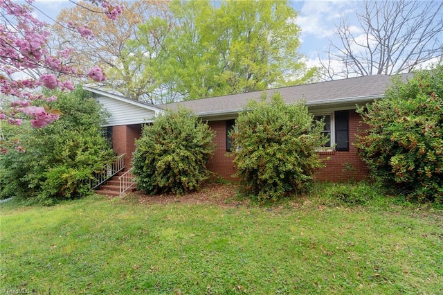 view of side of home featuring brick siding and a yard