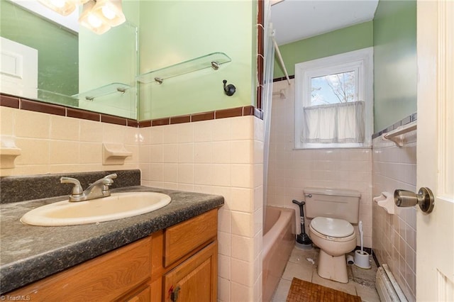 full bathroom featuring tile patterned floors, toilet, vanity, a baseboard heating unit, and tile walls