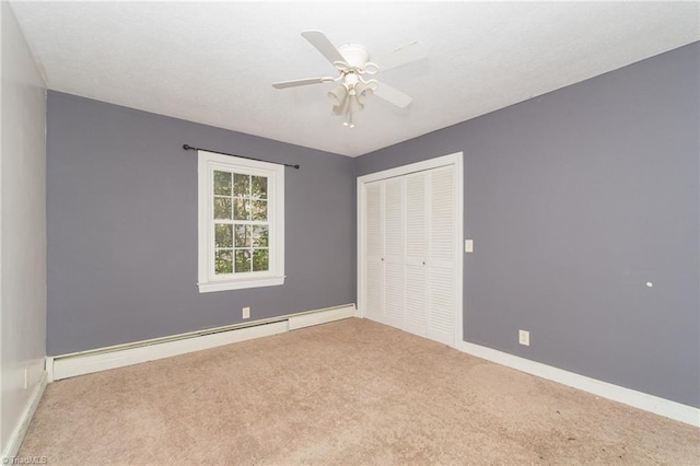 unfurnished bedroom with a closet, carpet floors, a baseboard heating unit, baseboards, and ceiling fan