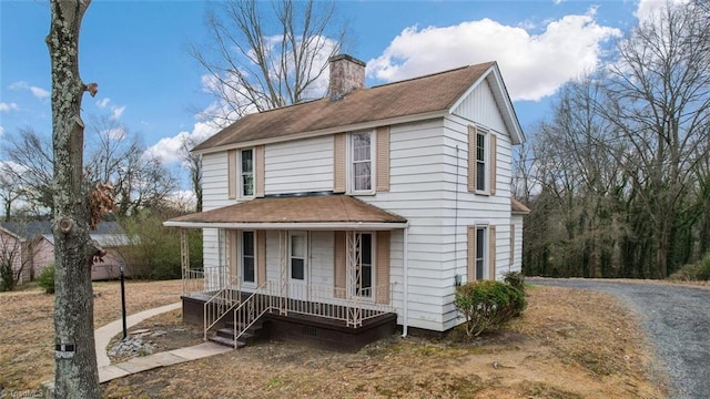 view of front of home featuring roof with shingles, covered porch, and a chimney
