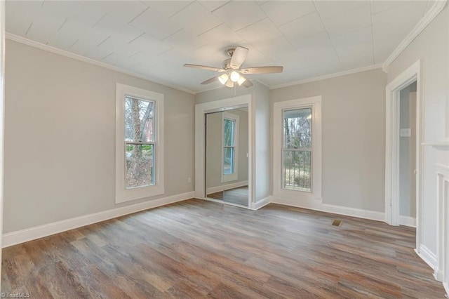 spare room featuring crown molding, a ceiling fan, wood finished floors, and baseboards