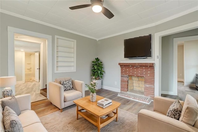 living room with crown molding, ceiling fan, a brick fireplace, and light wood-style flooring