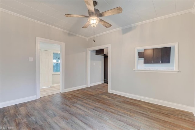 unfurnished room featuring wood finished floors, a ceiling fan, crown molding, and baseboards