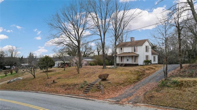 traditional home featuring driveway and a chimney