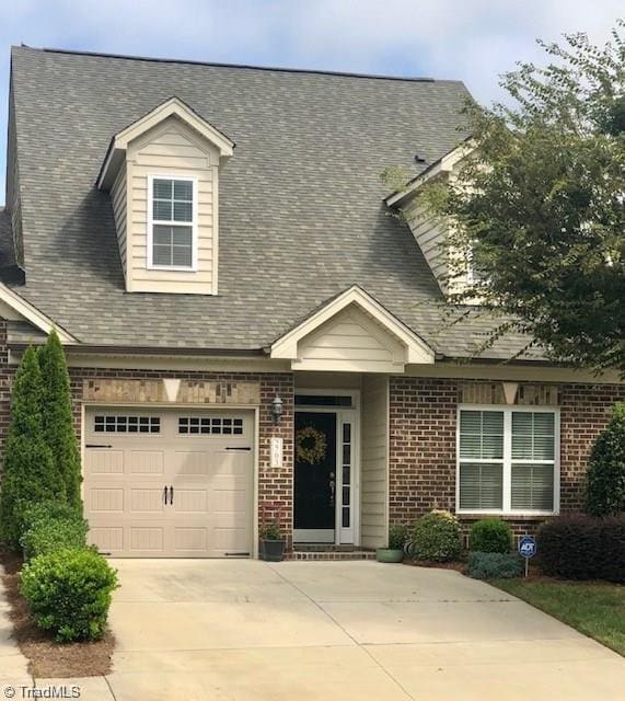 cape cod-style house with brick siding and concrete driveway