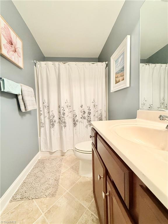 bathroom featuring tile patterned flooring, toilet, vanity, and baseboards