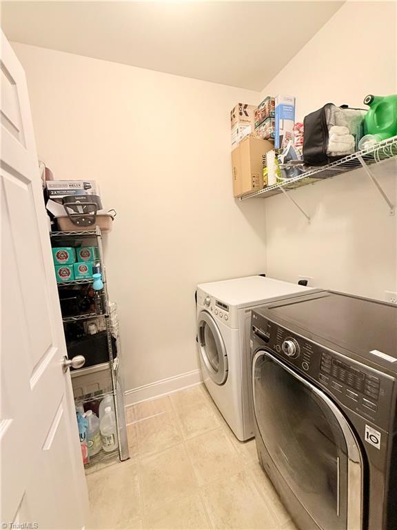 washroom with laundry area, separate washer and dryer, and baseboards