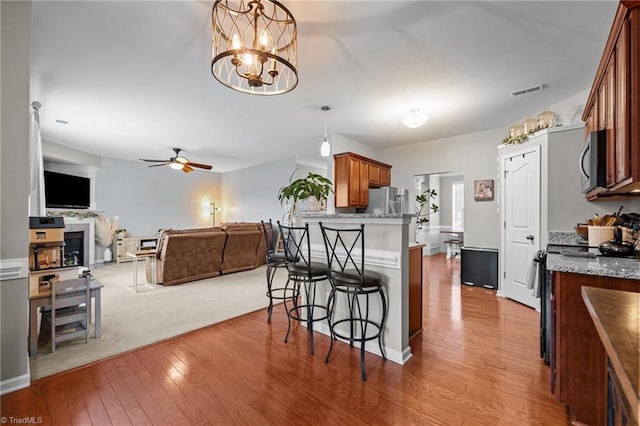 183 Kentland Ridge Dr, Kernersville, NC 27284 - kitchen featuring appliances with stainless steel finishes, a breakfast bar area, light wood-style floors, open floor plan, and a fireplace