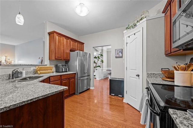 183 Kentland Ridge Dr, Kernersville, NC 27284 - kitchen featuring appliances with stainless steel finishes, a sink, light wood-type flooring, light stone countertops, and brown cabinetry