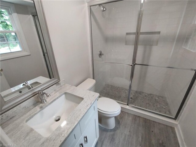 bathroom featuring walk in shower, wood-type flooring, vanity, and toilet