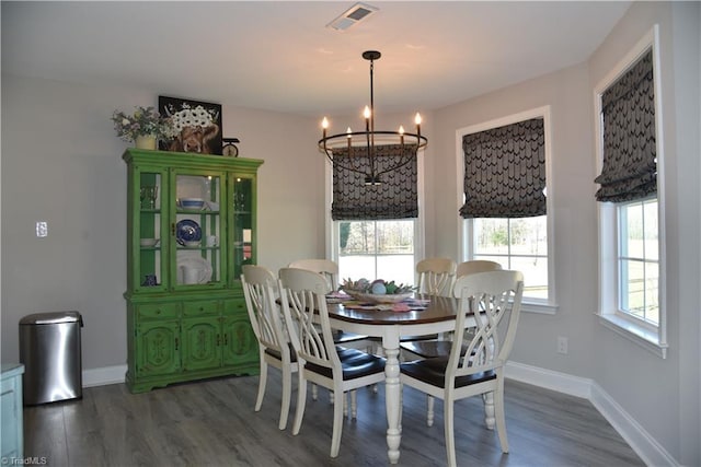 dining space with dark wood finished floors, baseboards, visible vents, and a chandelier