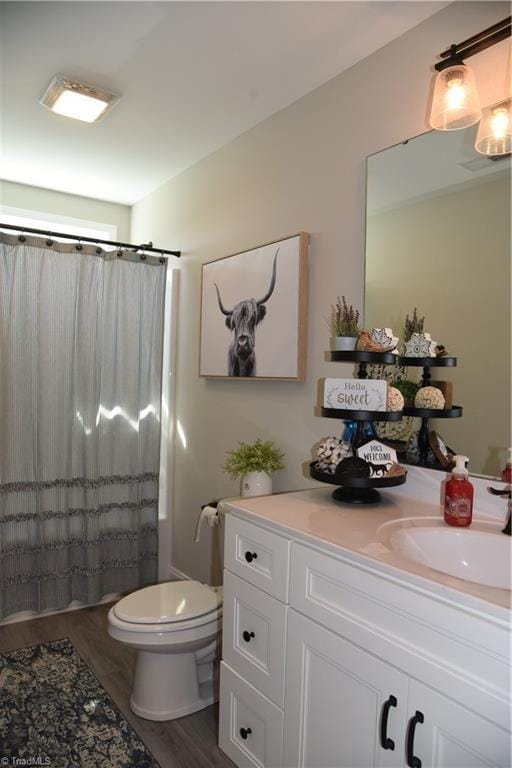 full bath featuring vanity, a shower with shower curtain, toilet, and wood finished floors