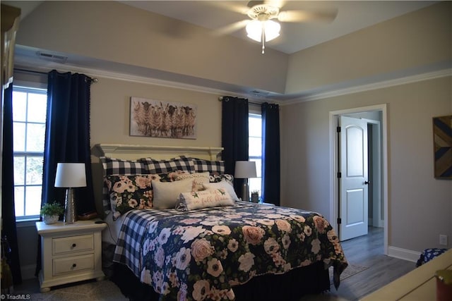 bedroom with multiple windows, baseboards, and wood finished floors