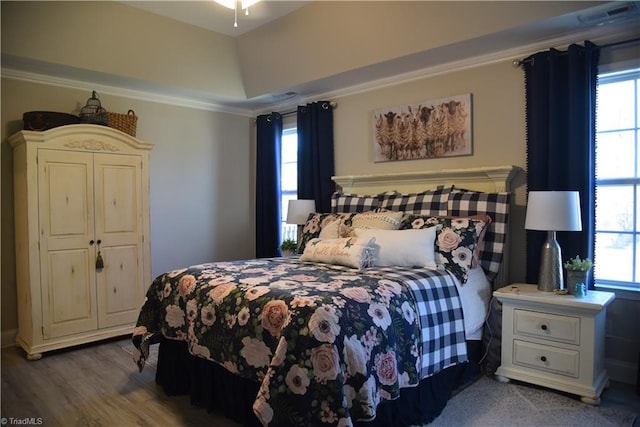 bedroom with multiple windows, wood finished floors, visible vents, and ornamental molding