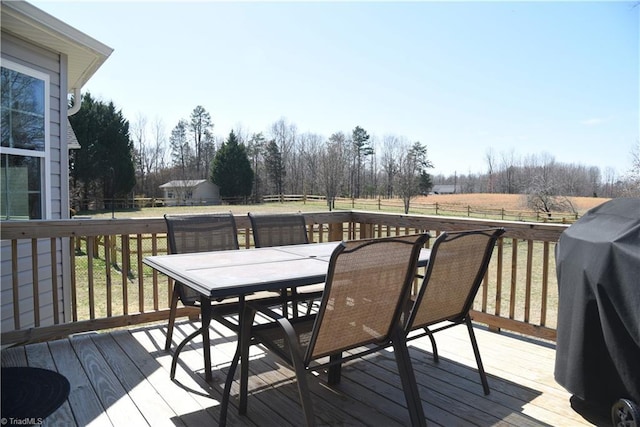 wooden deck with outdoor dining space, fence, a lawn, and a grill