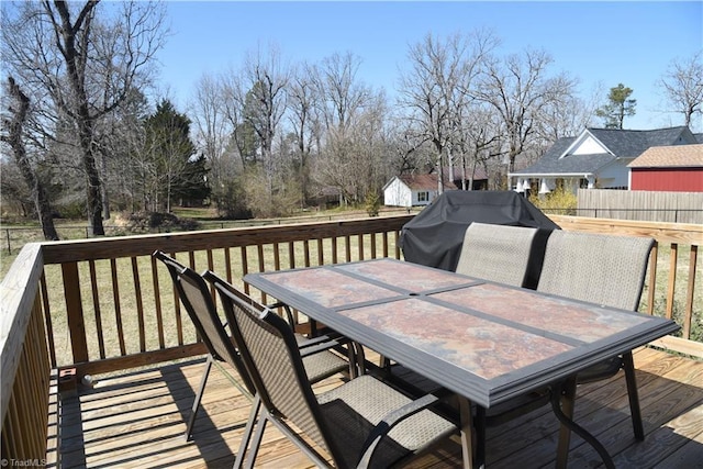 wooden terrace with outdoor dining space, fence, a lawn, and grilling area