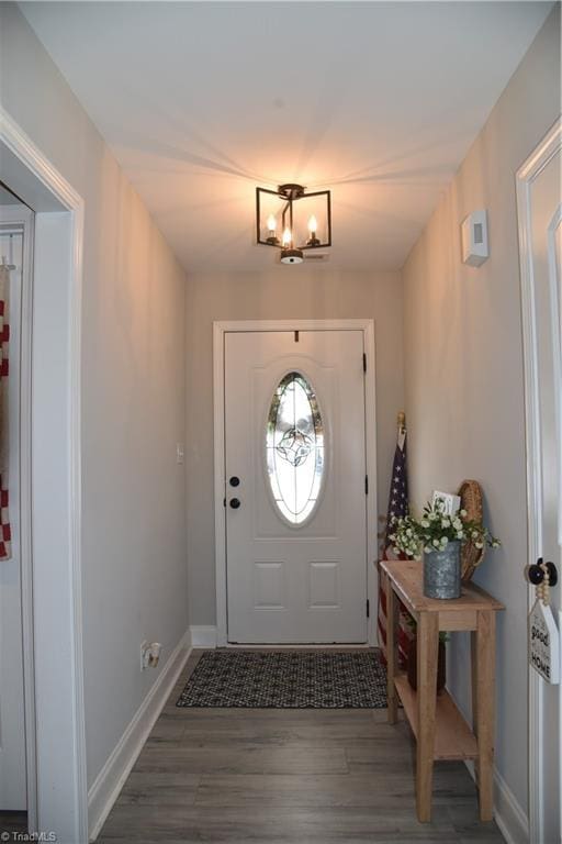 foyer featuring a chandelier, baseboards, and wood finished floors