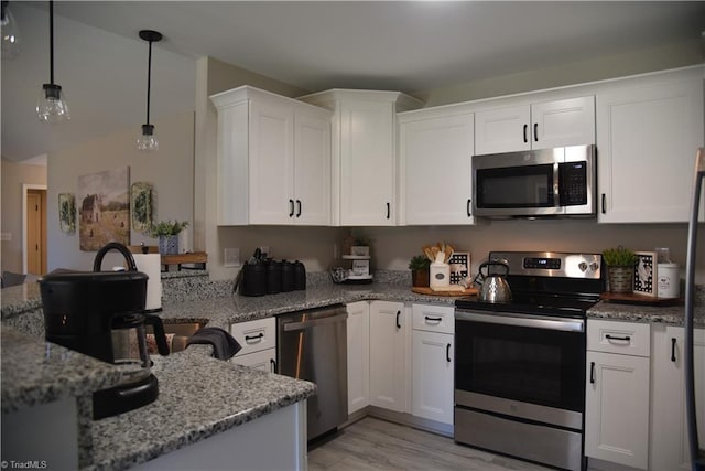 kitchen with light wood finished floors, pendant lighting, light stone counters, white cabinets, and stainless steel appliances