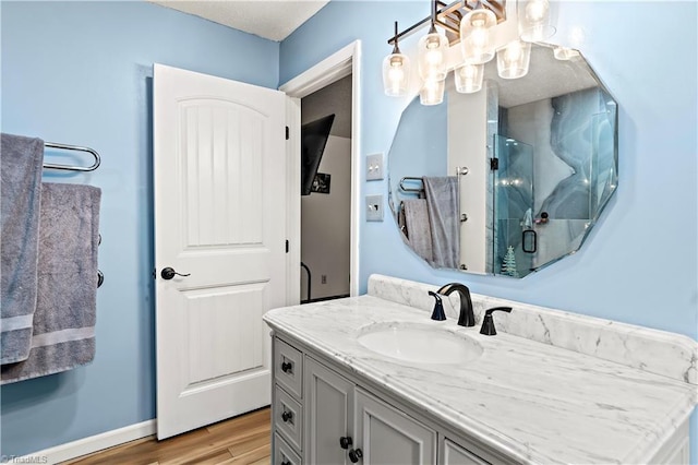 bathroom with vanity, wood finished floors, a stall shower, and baseboards