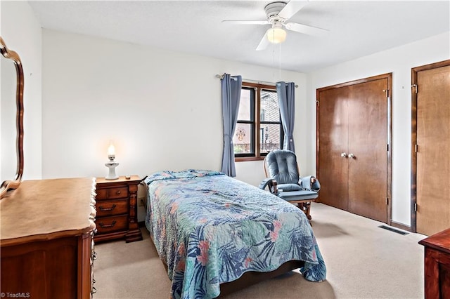 bedroom with visible vents, light carpet, two closets, and ceiling fan