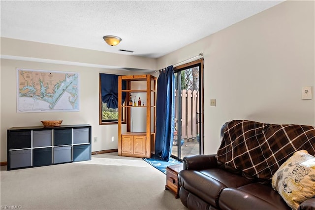 sitting room featuring baseboards, visible vents, carpet floors, and a textured ceiling