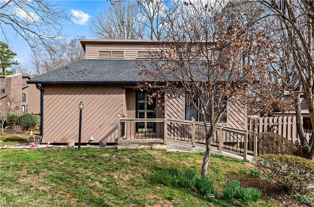 back of house featuring a shingled roof, a yard, and fence