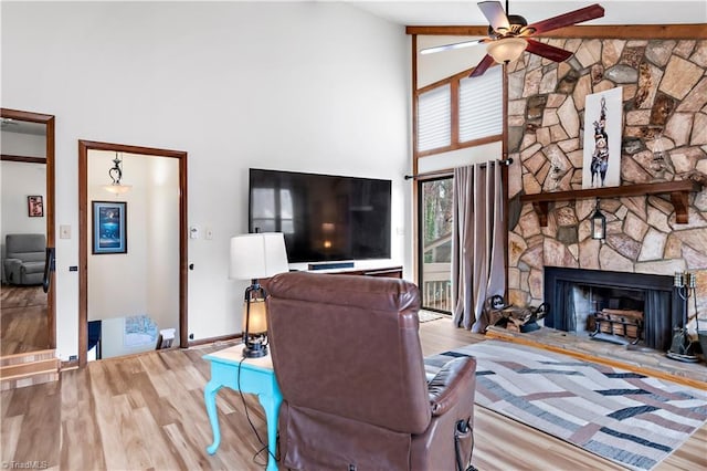 living area with high vaulted ceiling, wood finished floors, a fireplace, baseboards, and ceiling fan