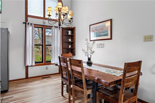 dining space featuring an inviting chandelier, baseboards, visible vents, and light wood finished floors