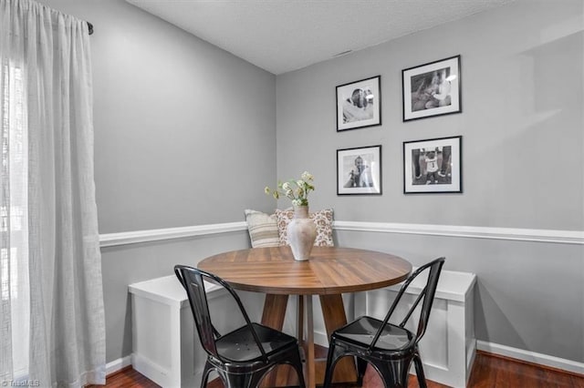 dining room featuring a textured ceiling, breakfast area, baseboards, and wood finished floors