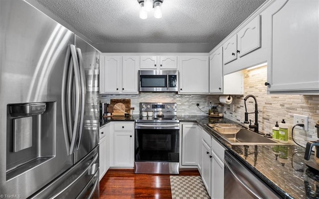 kitchen featuring a sink, tasteful backsplash, dark wood-style floors, appliances with stainless steel finishes, and white cabinets