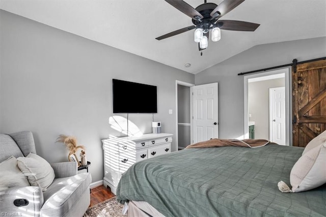 bedroom featuring baseboards, a barn door, vaulted ceiling, wood finished floors, and a ceiling fan