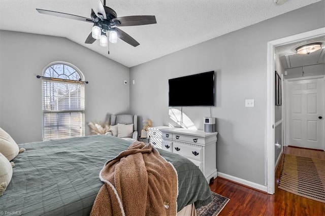 bedroom featuring wood finished floors, baseboards, attic access, vaulted ceiling, and a textured ceiling