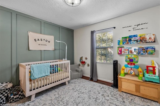 bedroom featuring a nursery area and a textured ceiling